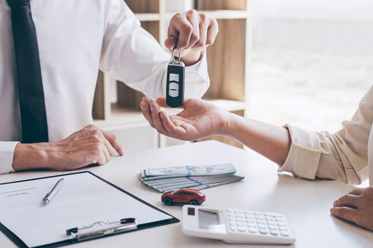 Car loan agent manager holding key of new car giving to woman client after signing good deal agreement contract