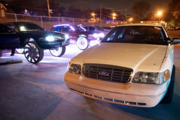 A group of modified Crown Victoria cars sit in a parking lot