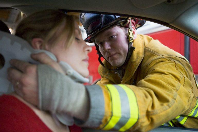 firefighters helping an injured woman in a car PRX5CF7