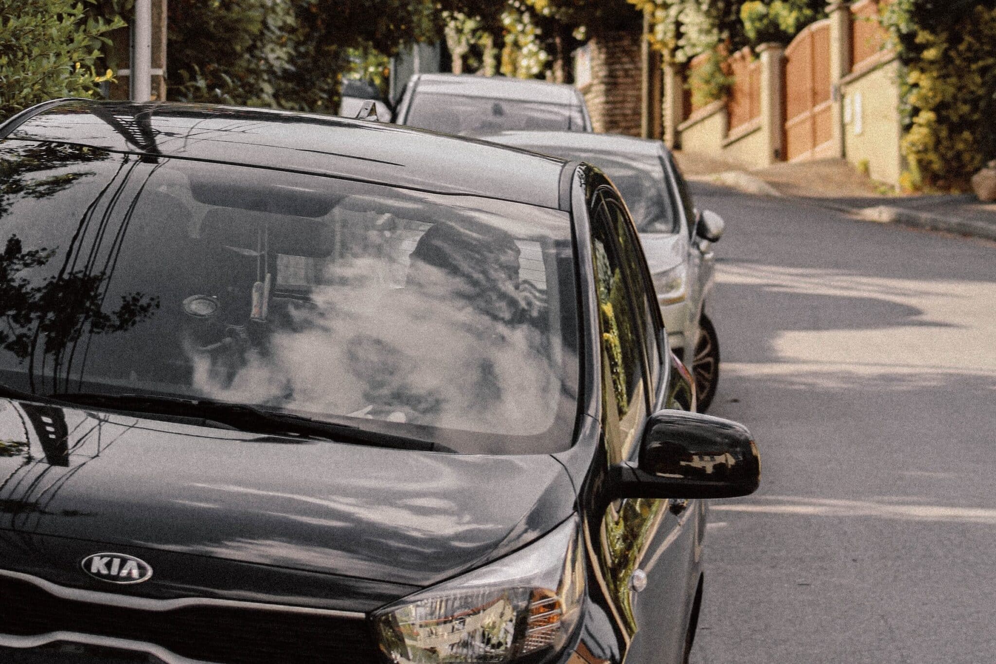 a black kia parked on a sunny street