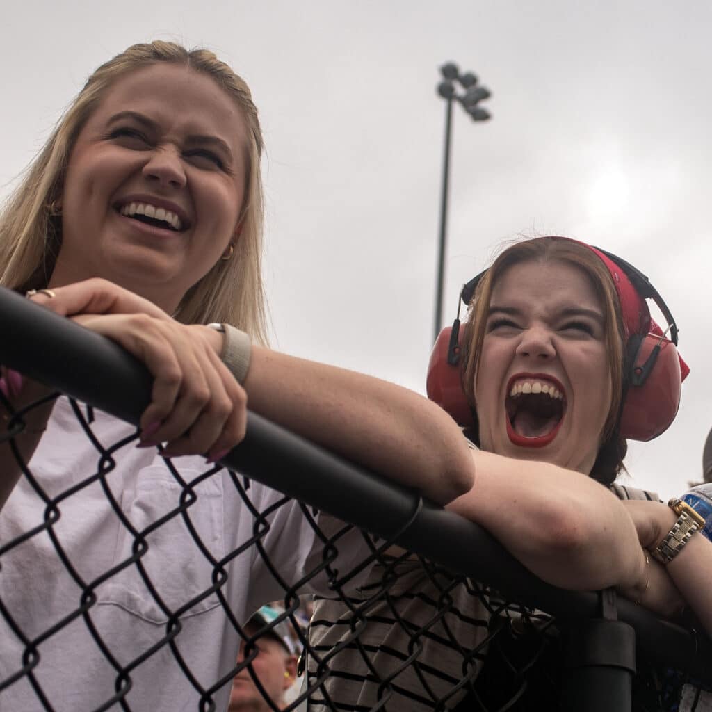 two nhra fans watching a race. one is shouting.