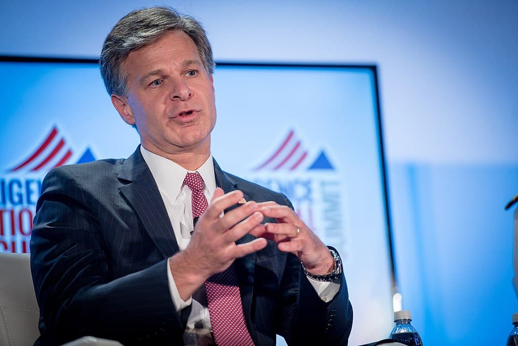 fbi director christopher wray speaking in front of a backdrop